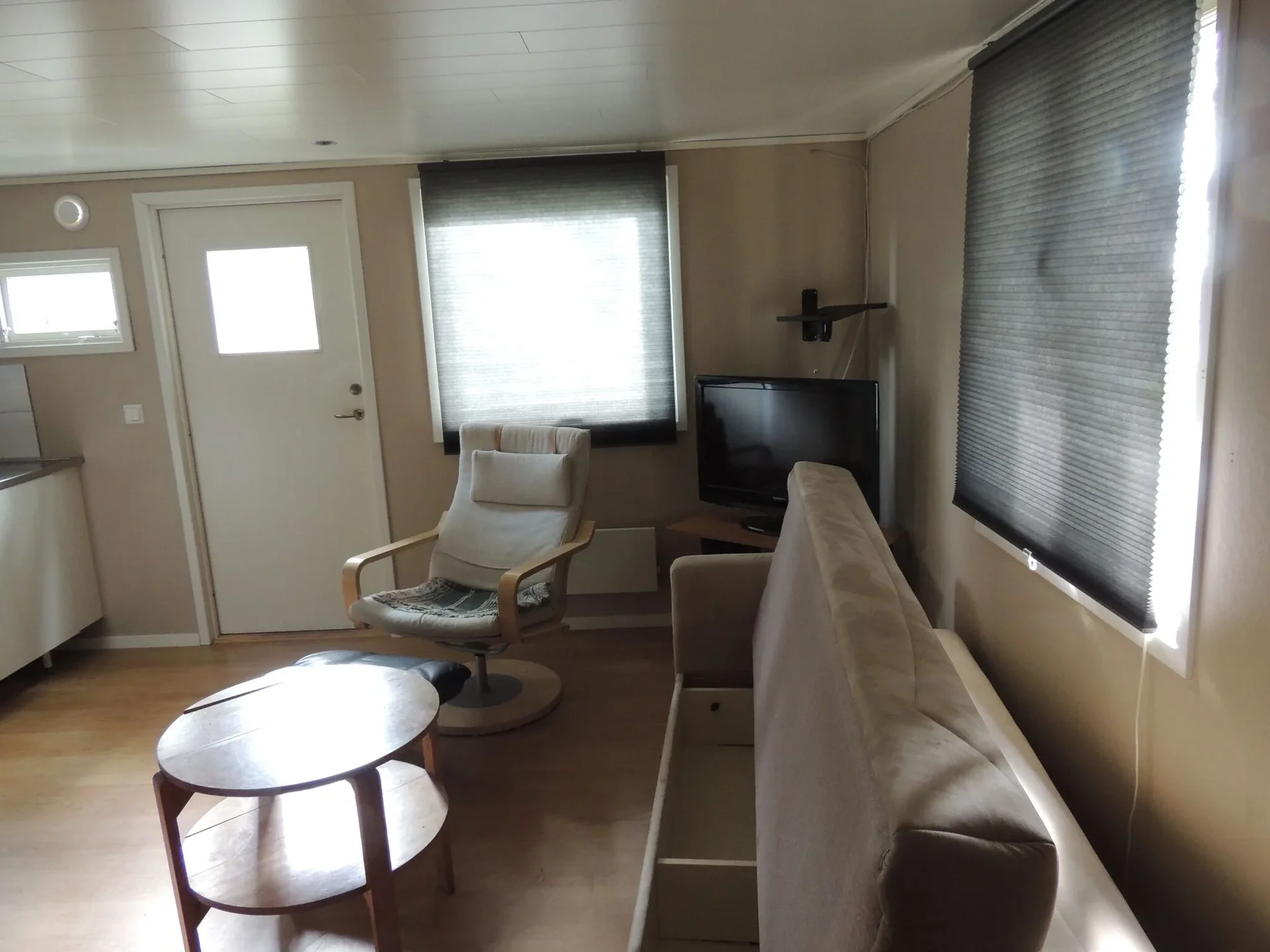 Vardagsrum i campingstuga med bäddsoffa och tv