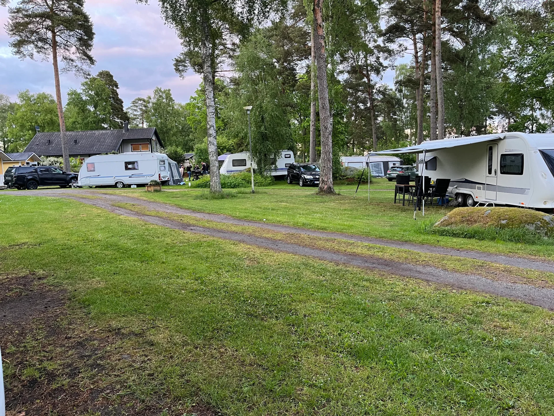 Campingplats i kvällsljus med husvagnar och husbilar