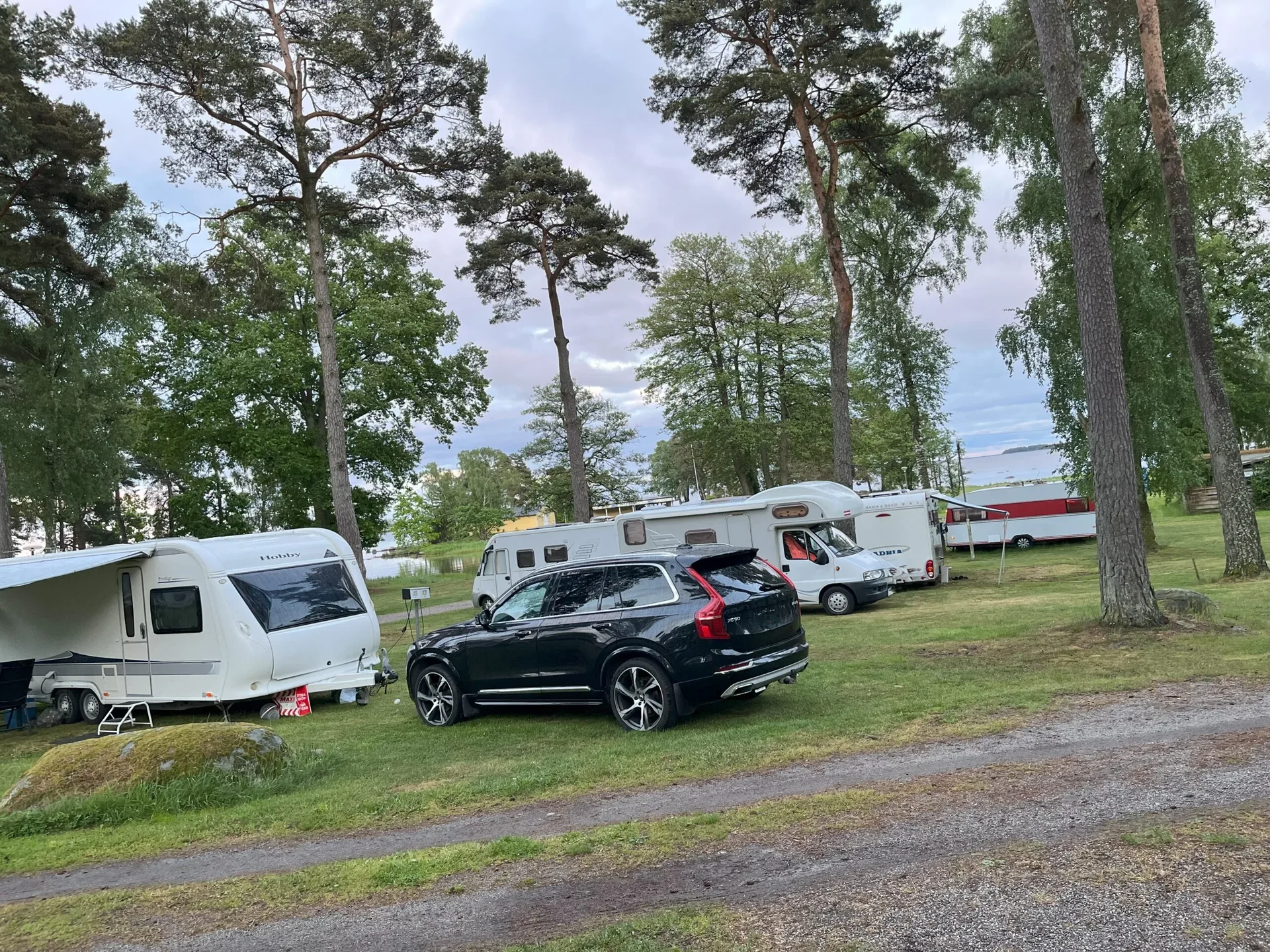 Husbilar och husvagnar uppställda nära vattnet i skymning