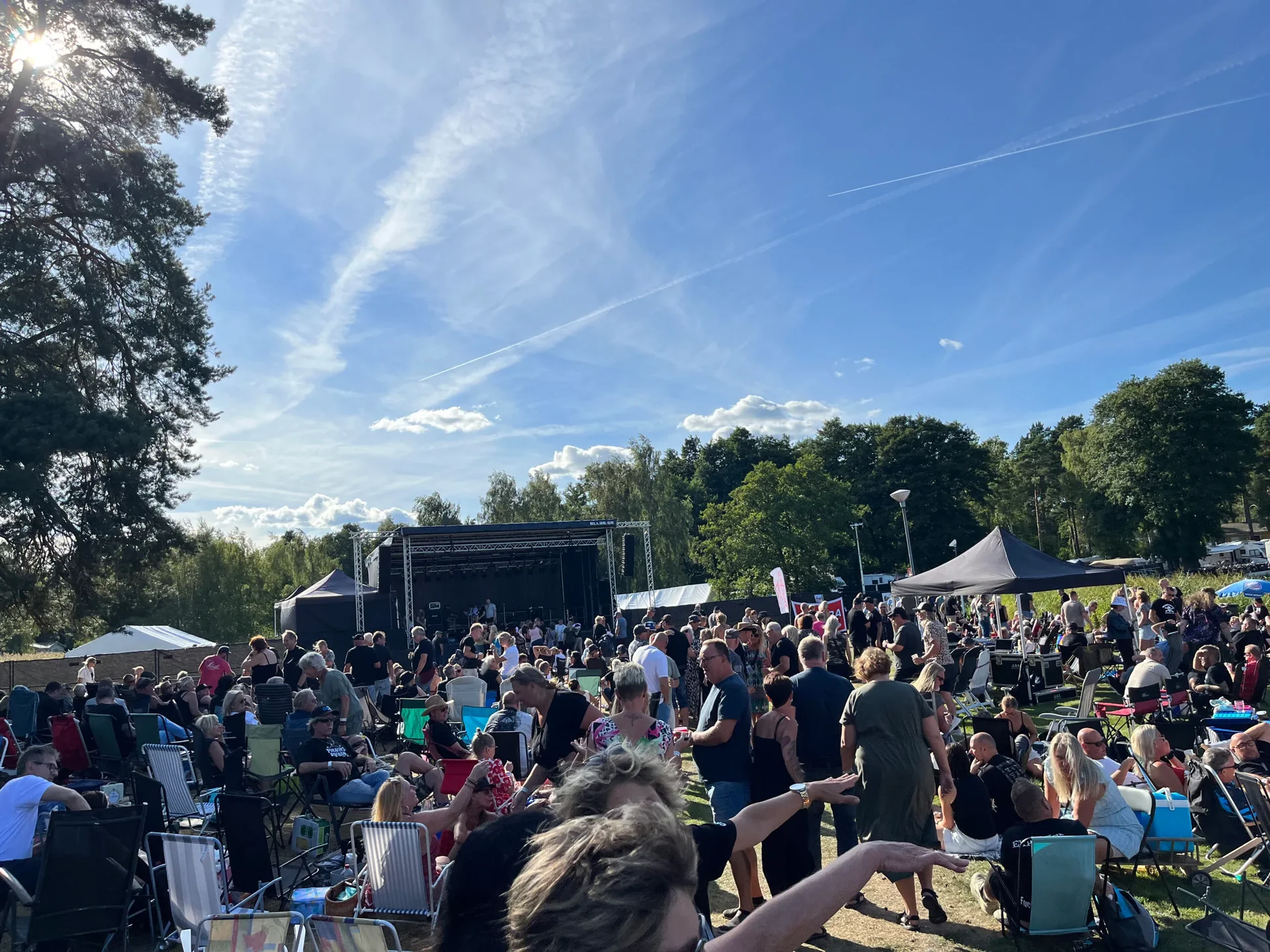Folksamling vid scen på sommarfestival i solsken