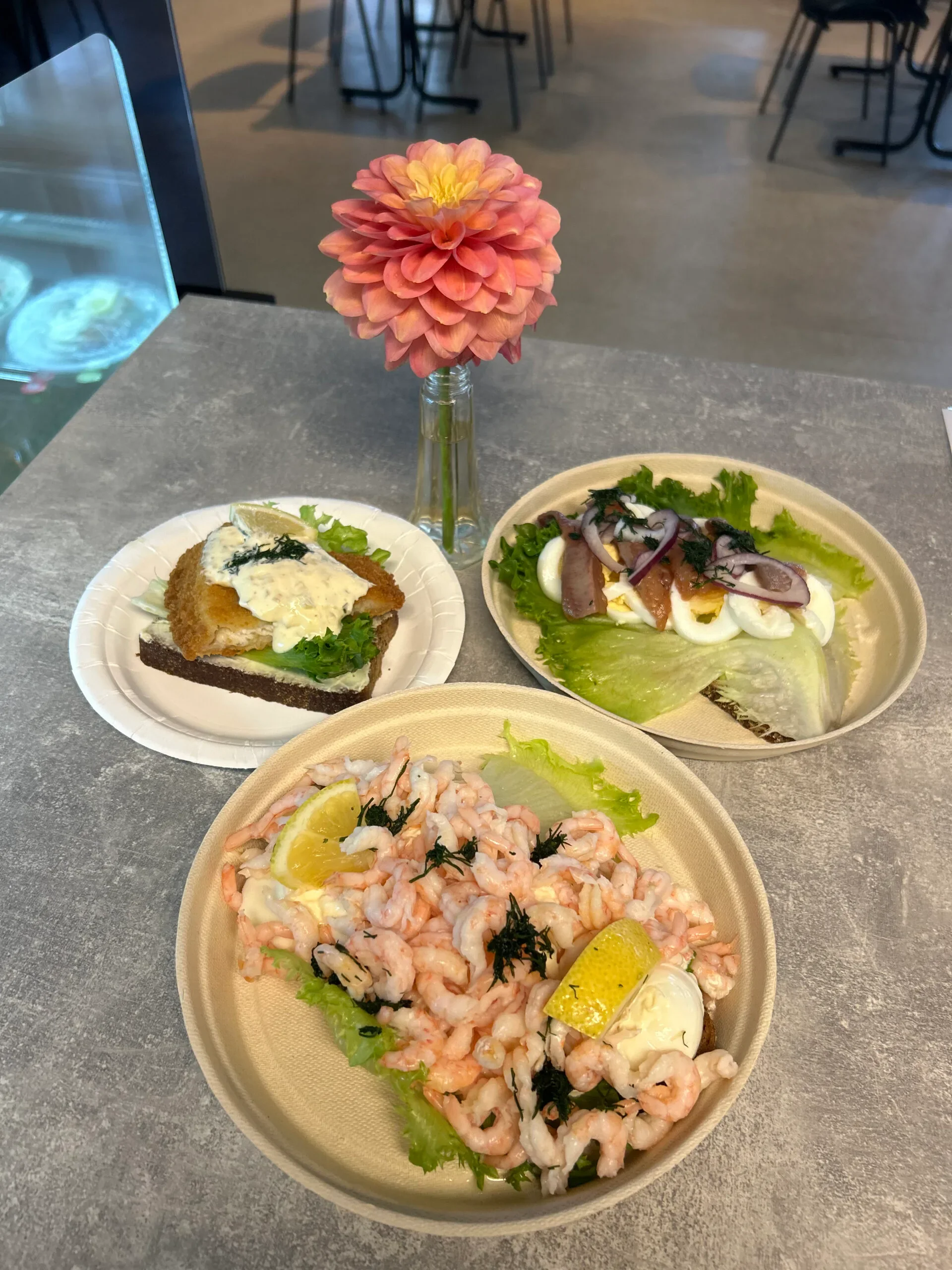 Räkmacka och fiskrätter på tallrikar med dahlia i vas på bordet